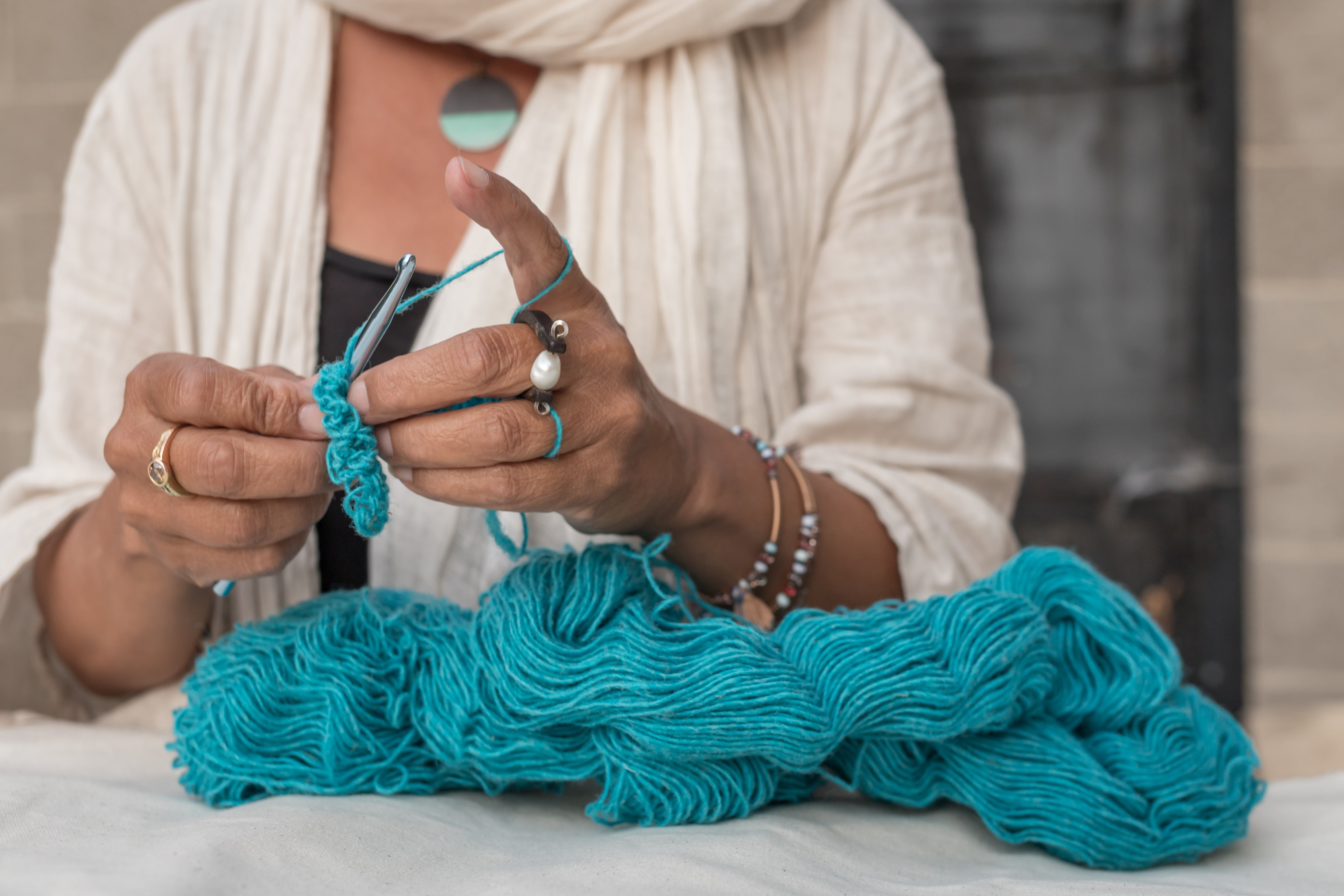 Woman with many rings knitting with Topsy Farms' Canadian wool yarn