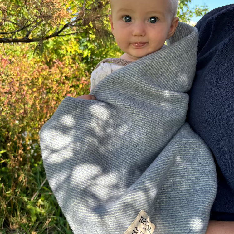 Baby wrapped in Topsy Farms' wool blanket