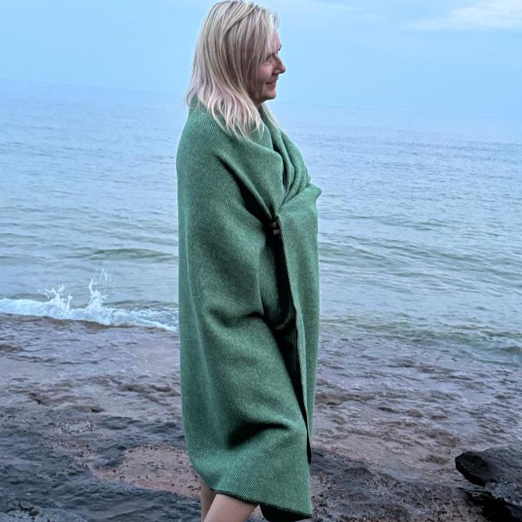 Topsy Farms' Canadian wool throw wrapped around a woman on a beach