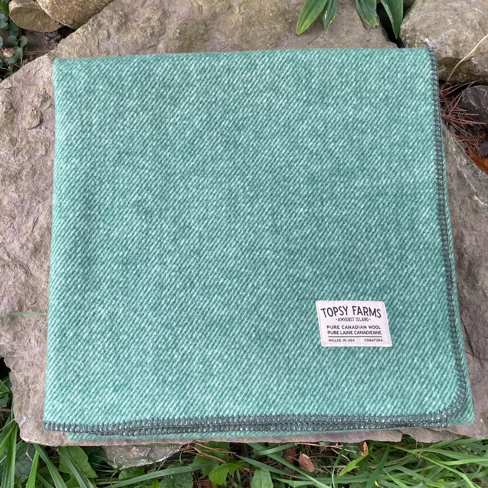 Topsy Farms' green tweed Canadian wool blanket on a rock