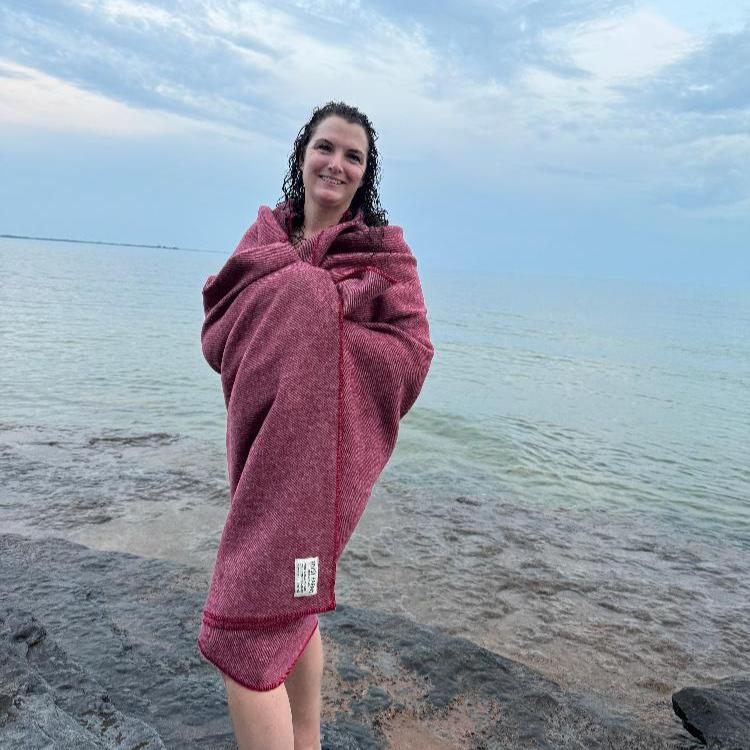 Topsy Farms' Canadian wool throw wrapped around a woman on a beach